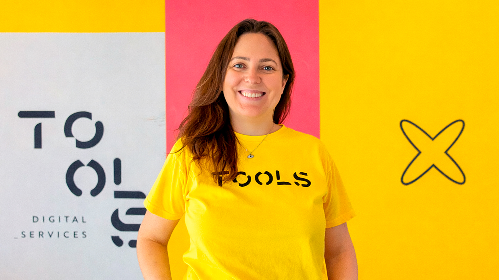 Mulher branca de camiseta amarela TOOLS sorrindo