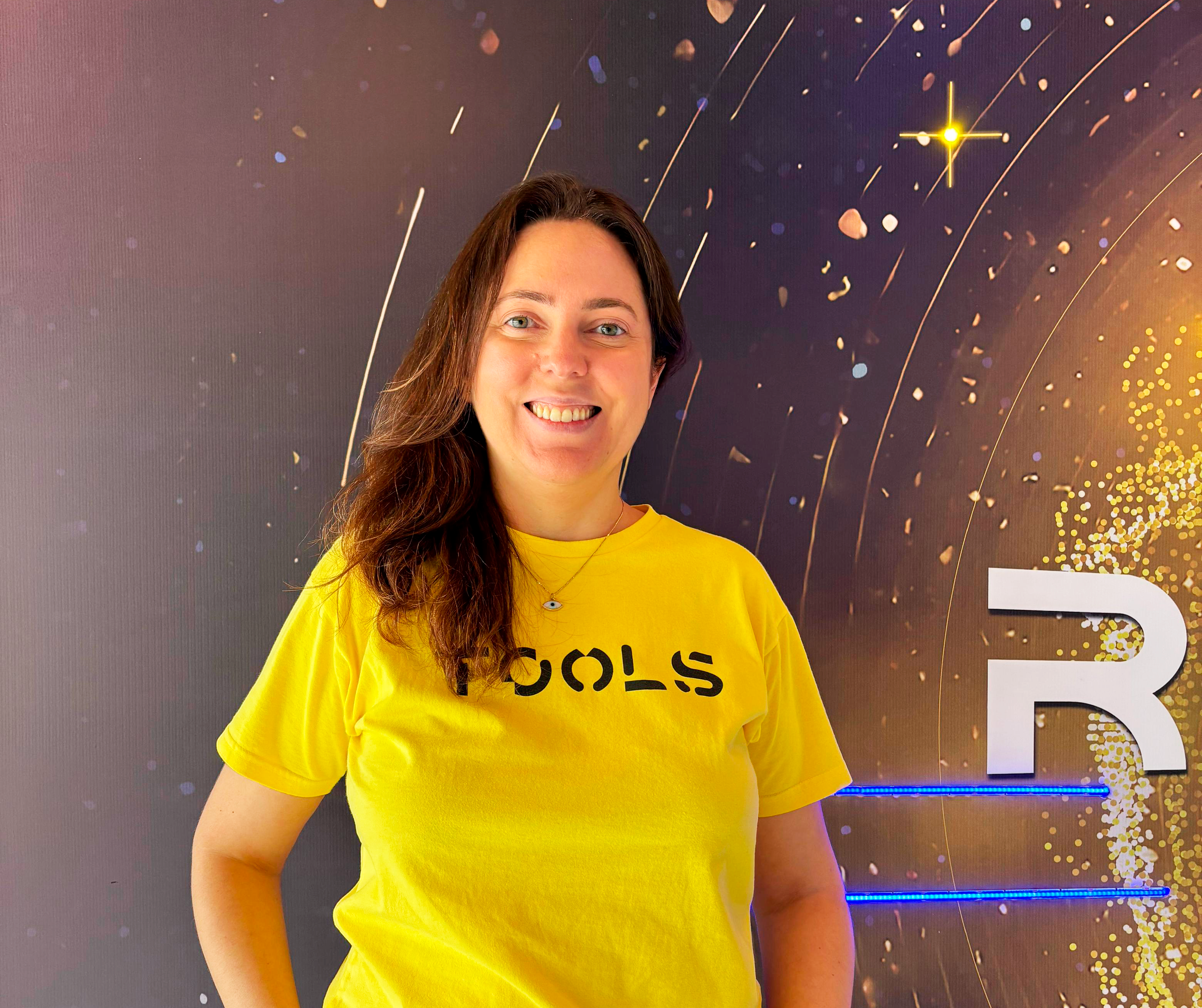 Mulher branca de camiseta amarela TOOLS sorrindo