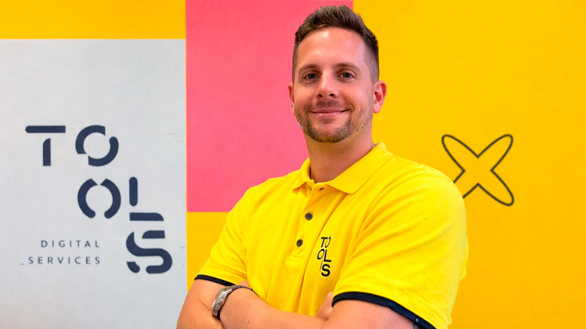 Homem branco de camisa polo amarela com braços cruzados