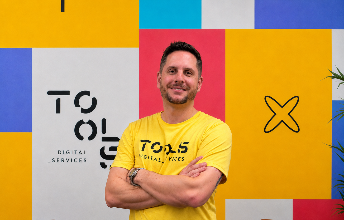 Homem branco de camisa polo amarela com braços cruzados