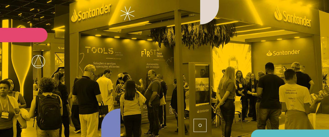Grupo de pessoas diversas em um stand de evento, com logo do Santander e da TOOLS ao fundo.