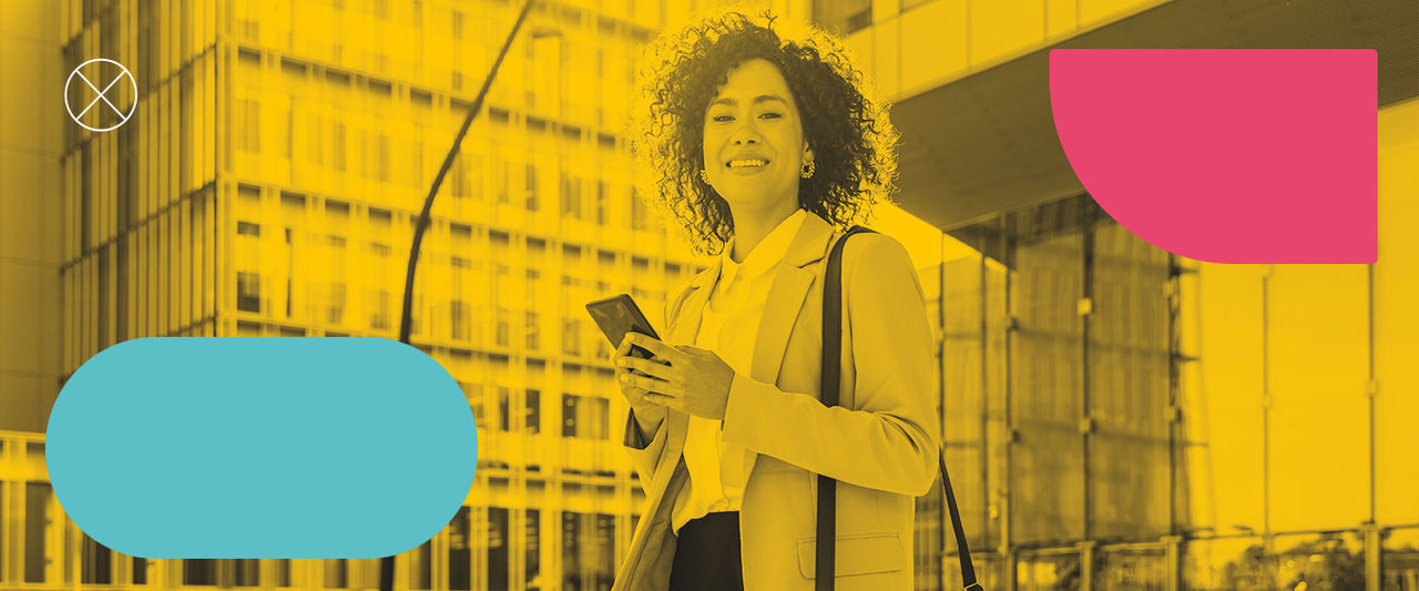 Mulher negra sorrindo para tela com celular em suas mãos