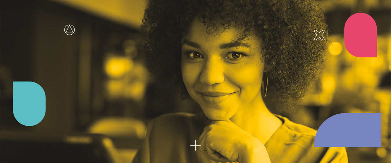 Mulher negra, de cabelos grisalhos, olha sorrindo para a câmera. 